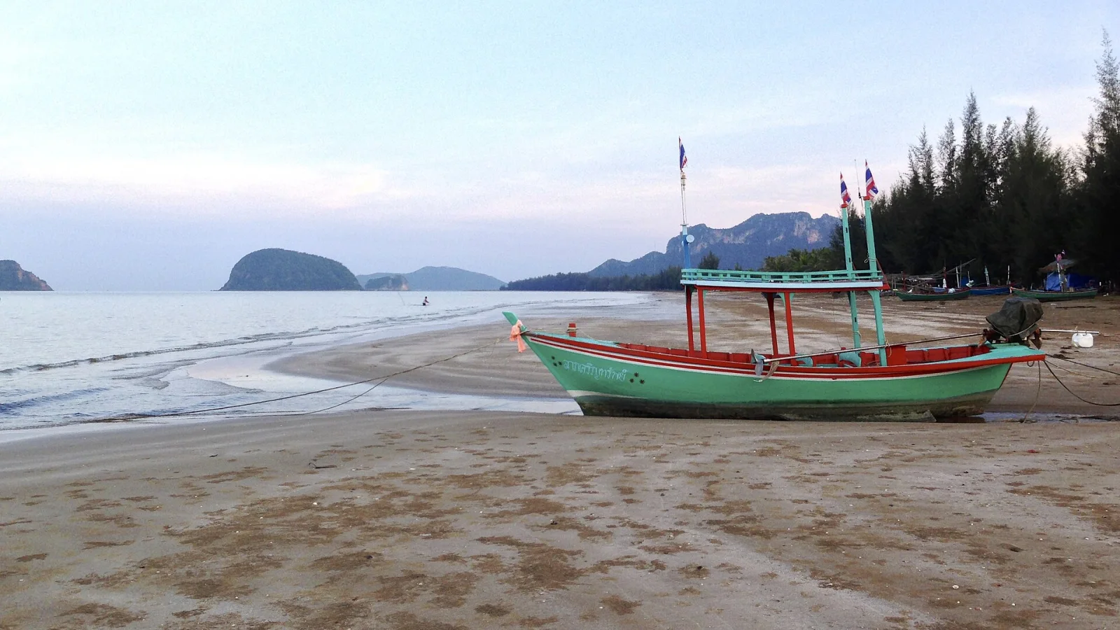 A painted Thai fishing boat pulled up on the beach at Dolphin Bay at dusk